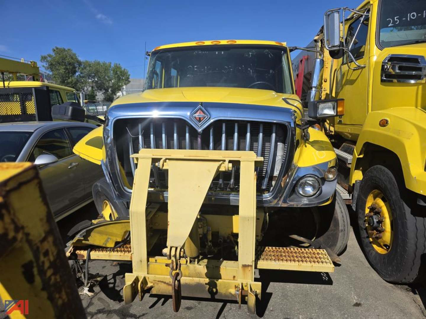 Truck front view showing a wheel loader attachment on the grille with International Workstar 7300 dump truck in yellow