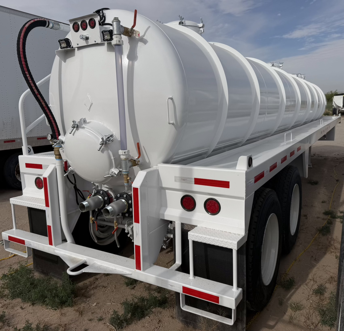 White vacuum tanker trailer with cylindrical tank on dual-axle chassis; rear view shows hoses, valves, and fittings; no legible model numbers visible.