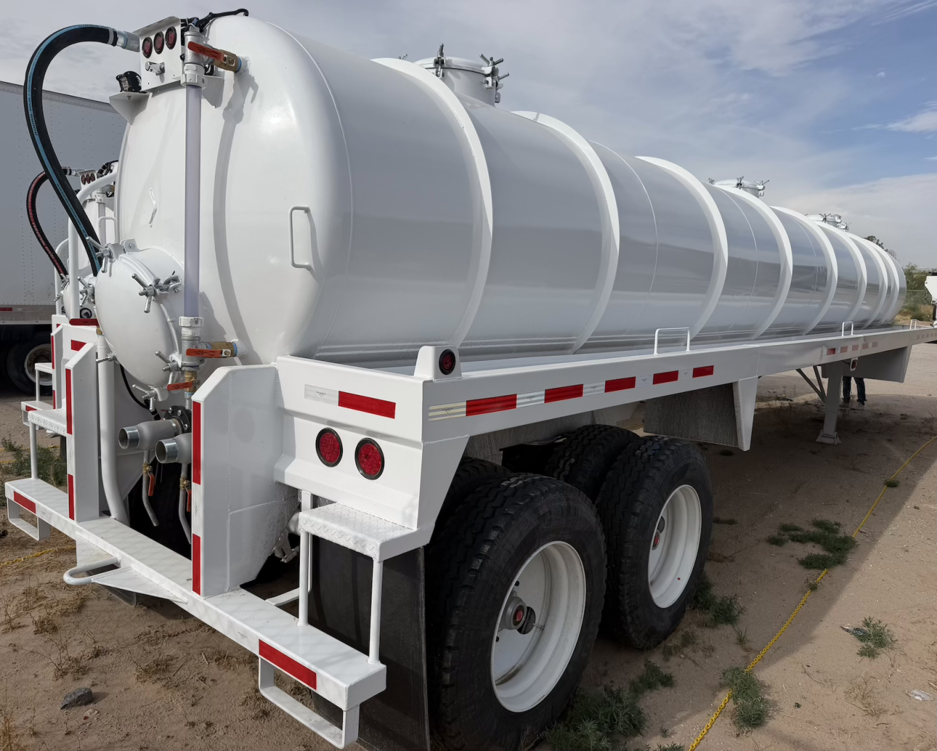 Intramet vacuum tanker trailer with a 130BBL (5,460 gal) stainless steel cylindrical tank on a dual-axle wheel chassis, rear loading/operating components visible.