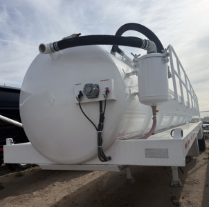 Vacuum trailer tank showing rear end with control panel and hoses attached.