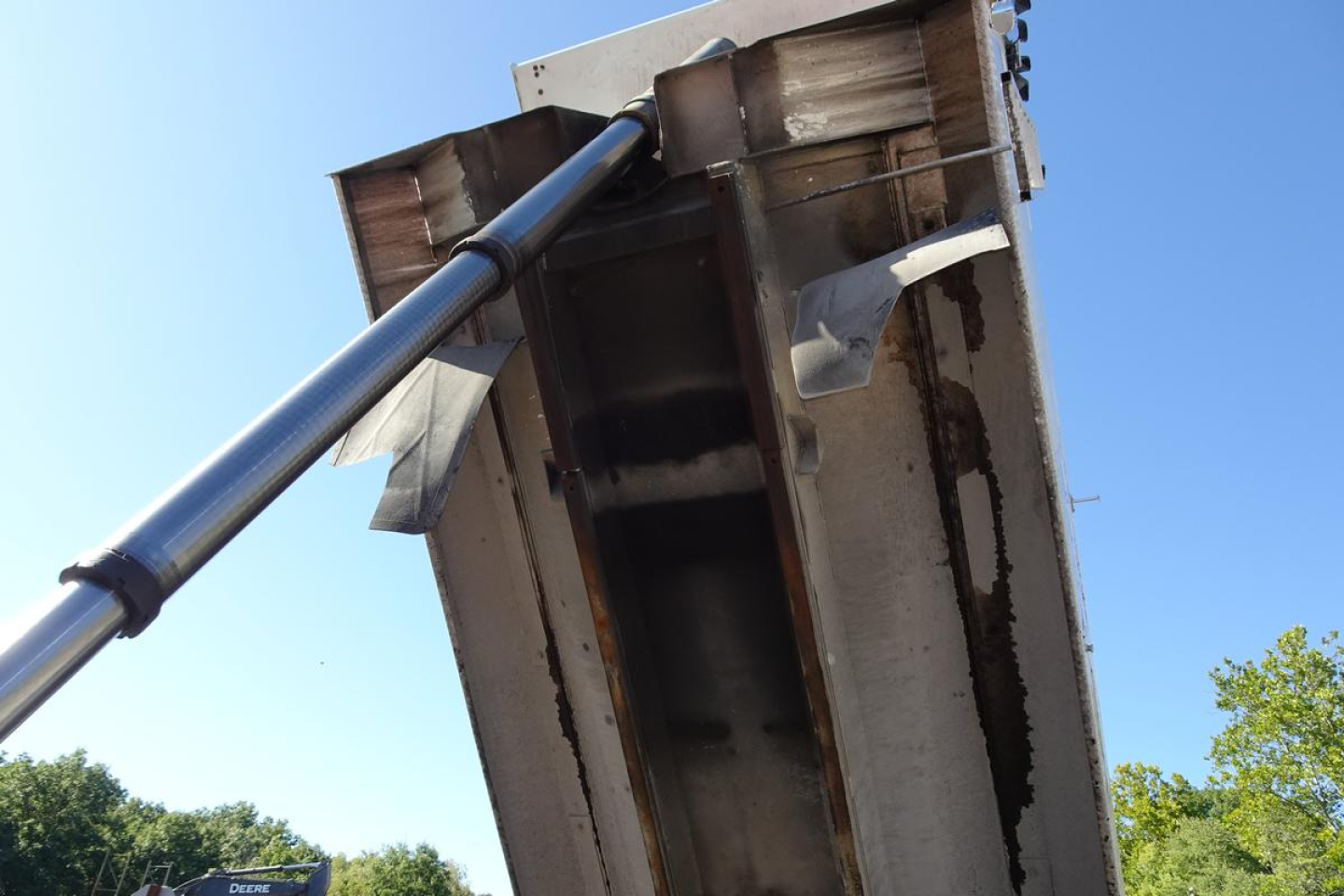 Vehicle equipment image showing dump truck bed with hydraulic piston and metal framework, viewed from below.