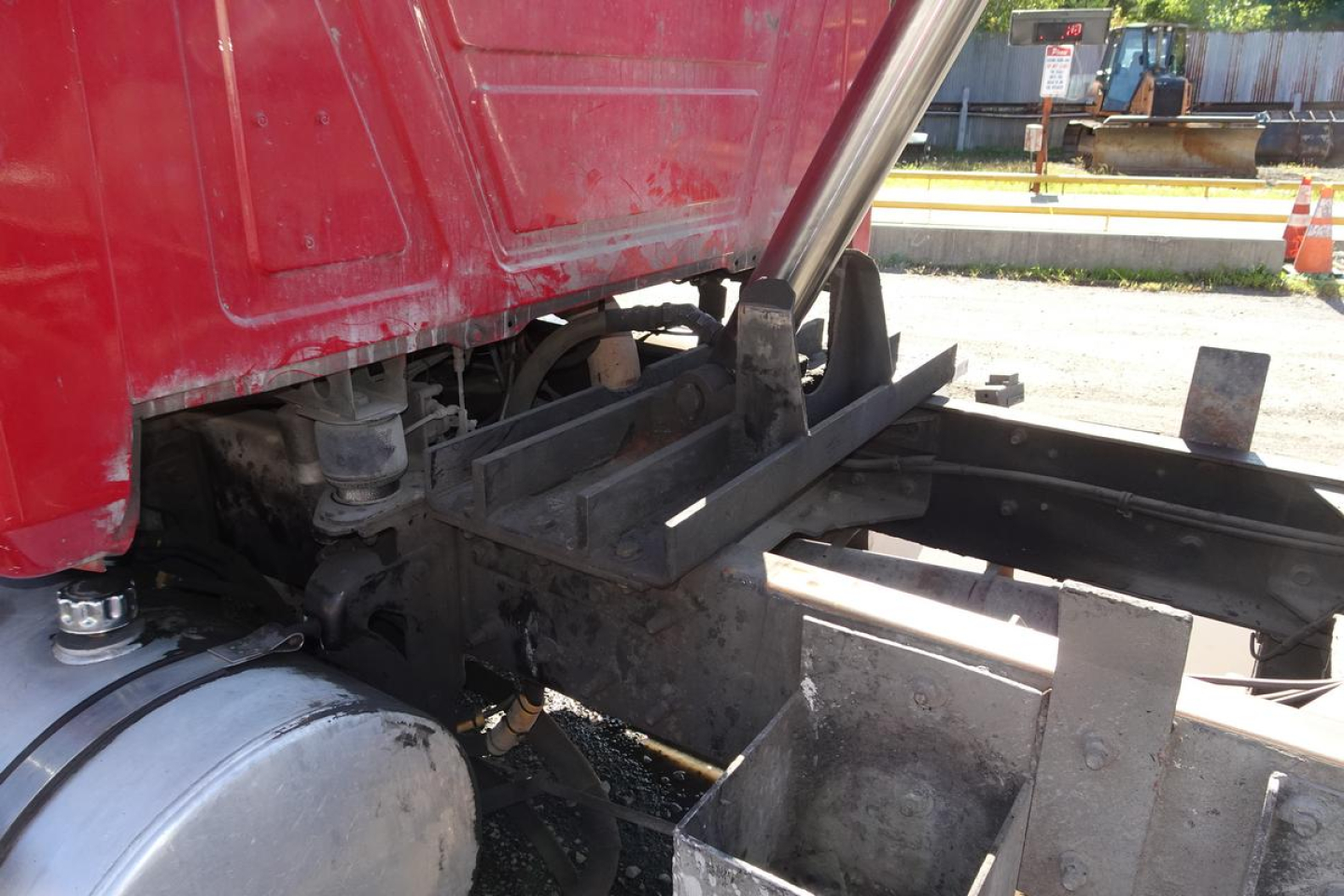 Truck cab and chassis area of a 2005 Mack CV (Granite) CV713 dump truck showing frame, hydraulic lines, and suspension components.