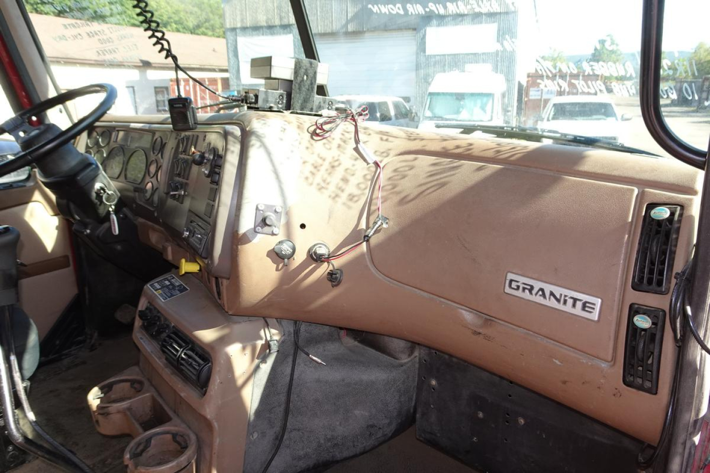Truck cab interior showing Mack Granite CV713 dashboard with beige panels and steering wheel.