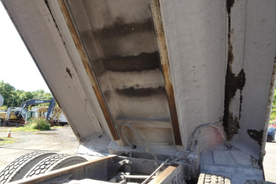 Dump truck bed showing hydraulic lift and interior of dump body with metal ribs and sidewalls visible.