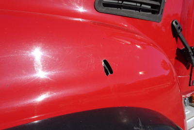 Front fender of a red Mack CV truck showing a dent/scratch on the hood area and a partial vent.