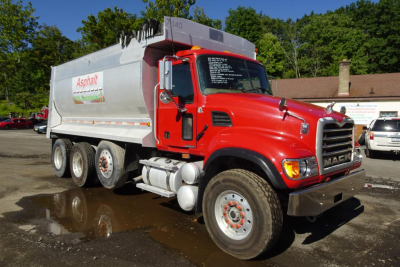 Truck cab shows red Mack CV (Granite) CV713 dump truck with silver dump body. Side shows Asphalt signage, large front grille, heavy-duty wheels, and tanker-style rear chassis.