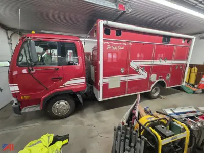 Fire truck showing a red Nissan UD 1800 rescue unit inside a garage with equipment nearby.