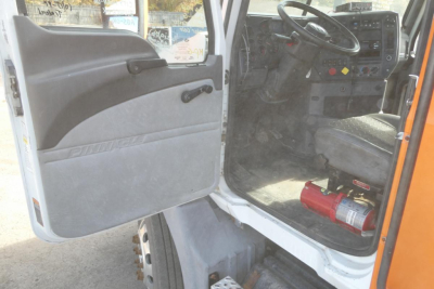 Truck cab interior showing steering wheel dashboard and open door with step and kick panel.