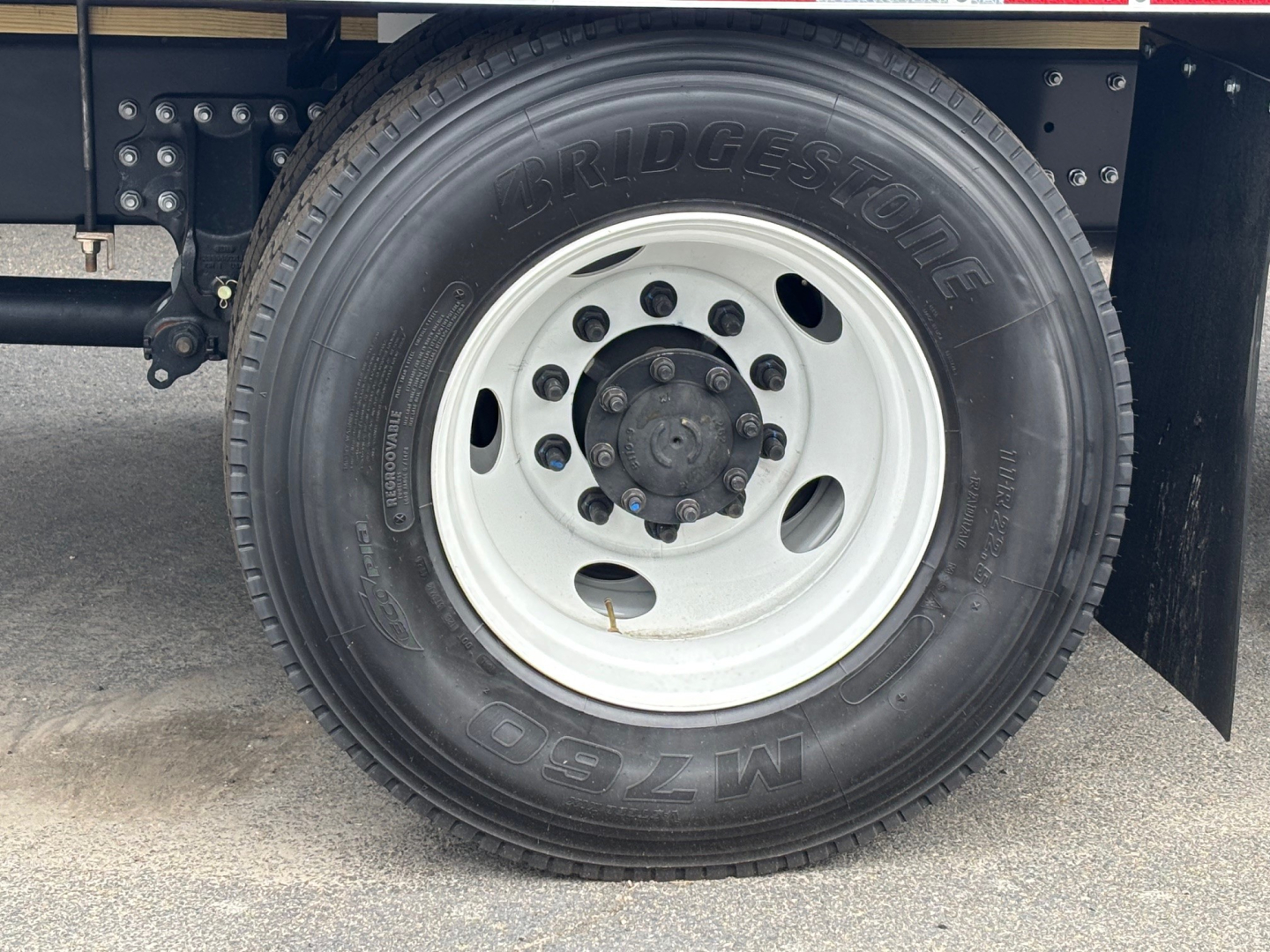 Mack MD6 wheel and Bridgestone tire showing steel white rim with lug nuts and hub, side of truck undercarriage visible