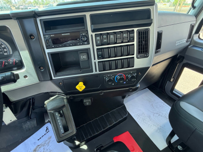 Dashboard and center console of a new 2026 Mack MD6 tractor with multiple switches, radio, climate controls, and a paper document on the passenger side.