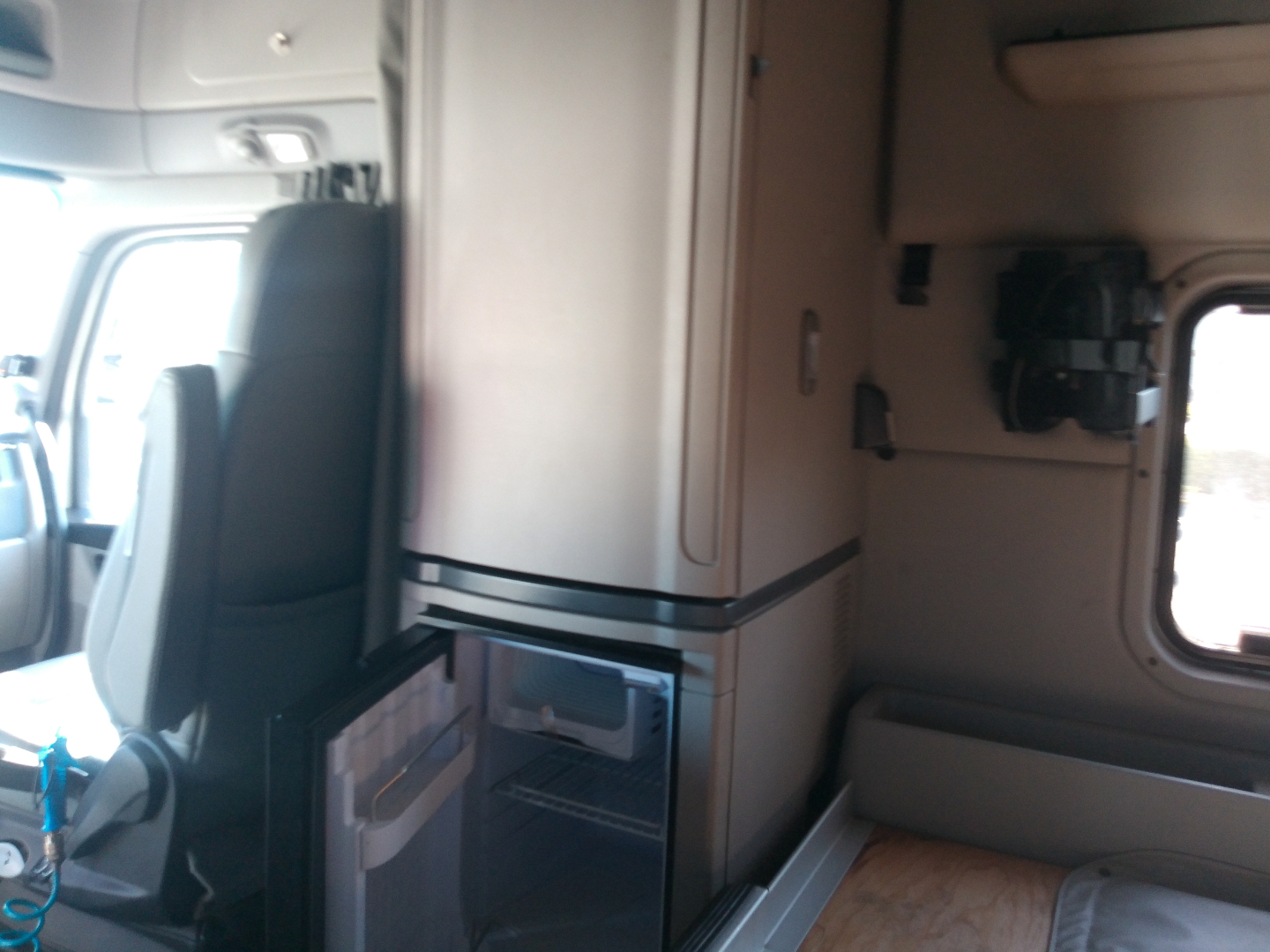 Peterbilt truck cab interior showing kitchenette area with refrigerator and storage cabinets