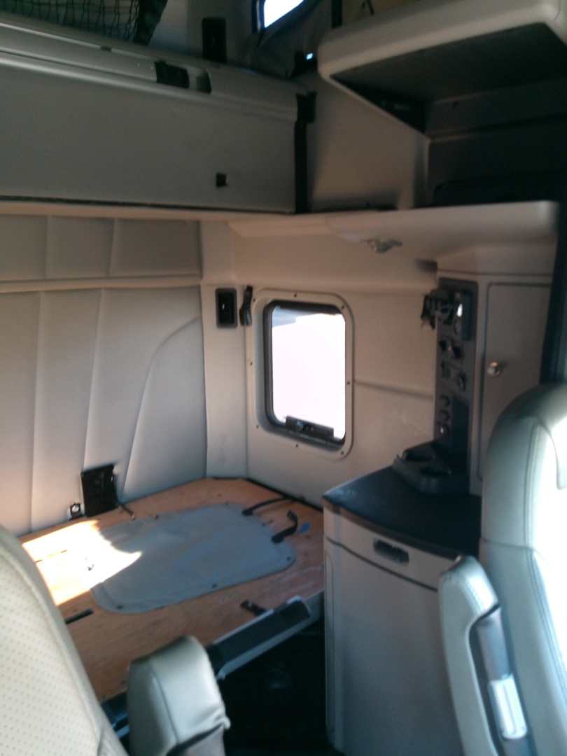 Peterbilt 579 truck cab interior showing sleeper area with window, side panel, and storage cabinet.