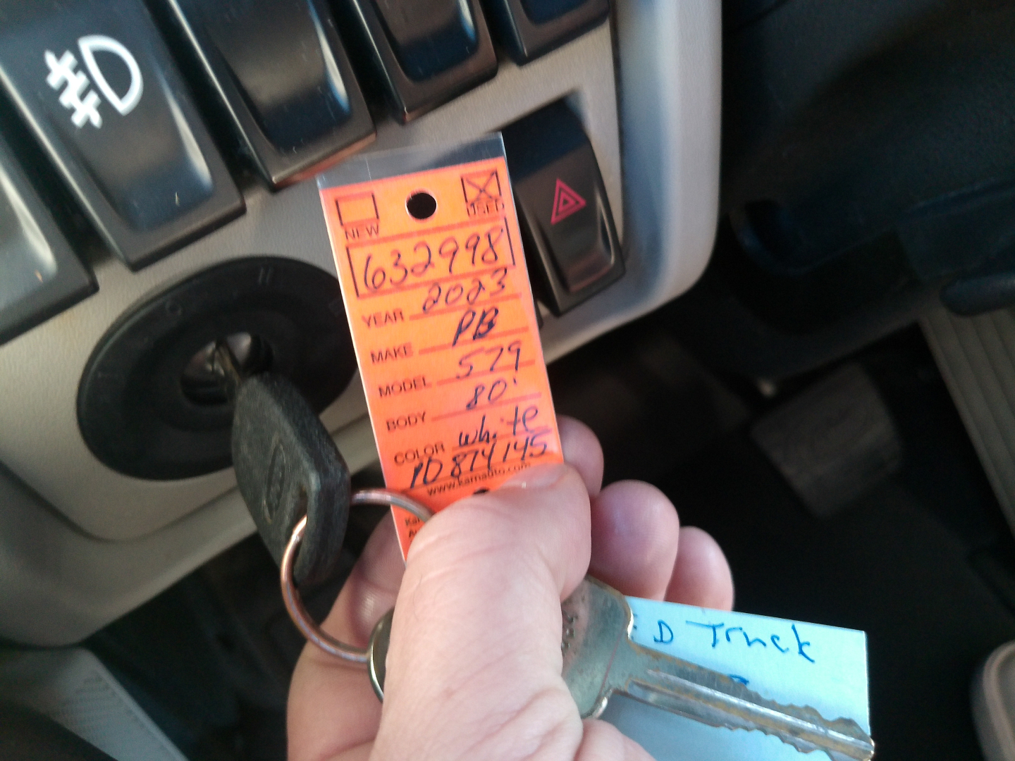 Peterbilt 579 dash area with ignition key inserted and orange inventory tag hanging from ignition switch.