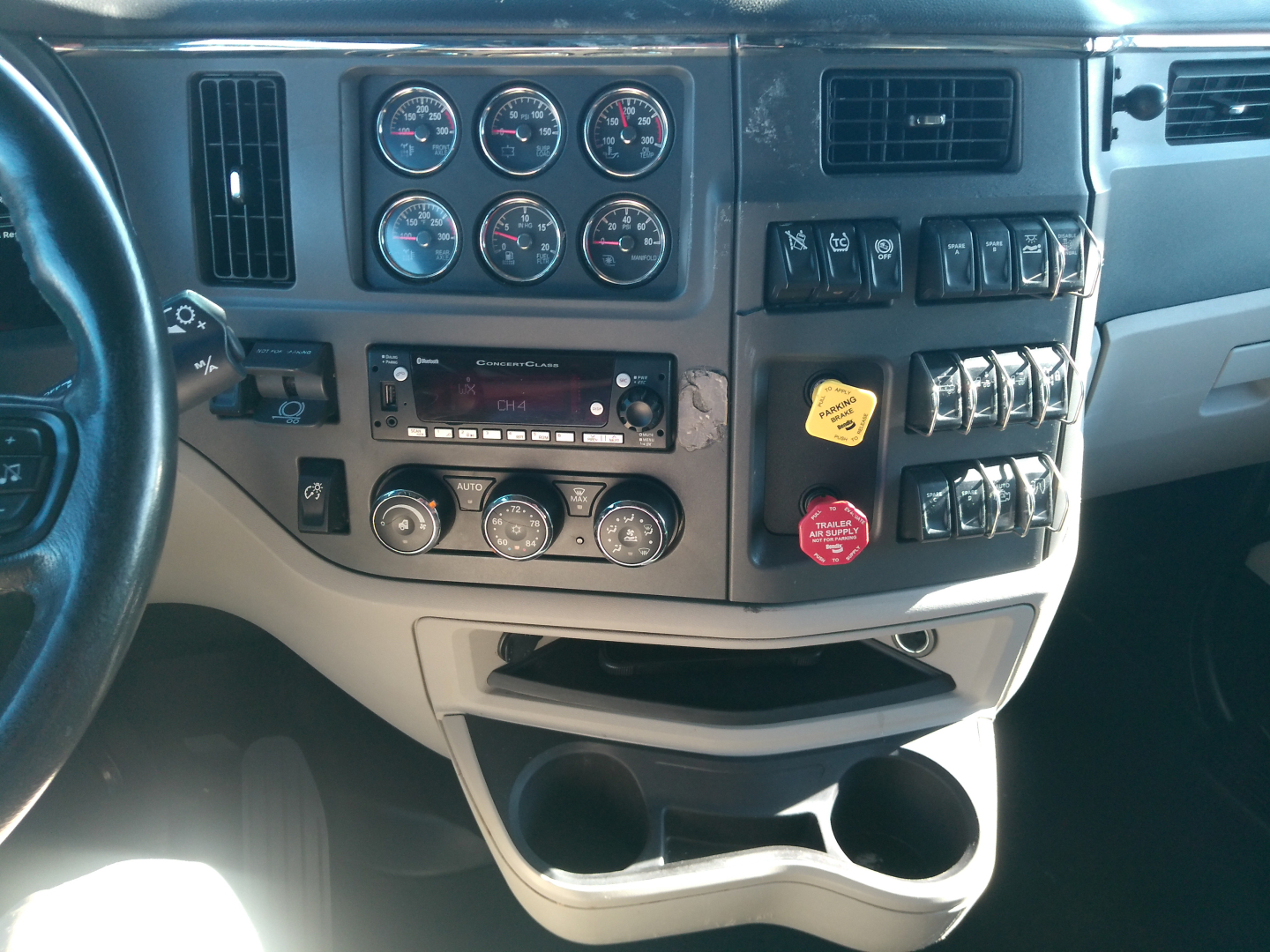 Peterbilt 579 truck dashboard view showing multiple gauges, switches, radio, climate controls, and storage compartments.