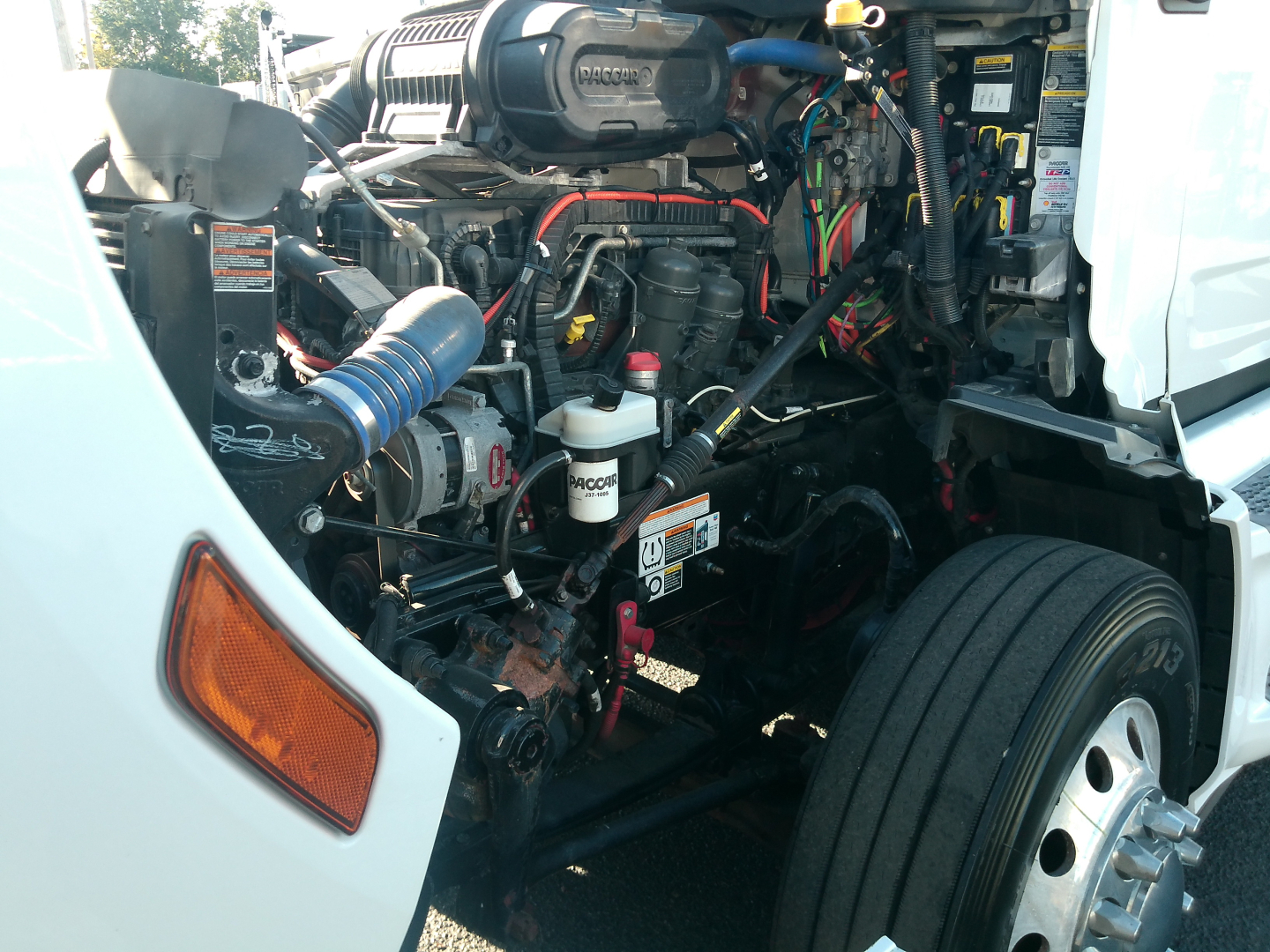 Peterbilt 579 engine bay showing coolant reservoir, hydraulic lines, and alternator in-service truck engine compartment.