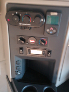 Dashboard panel of Peterbilt 579 showing climate control dials, display screen, and gear/shifter area.
