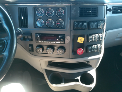 Peterbilt 579 truck dashboard view showing multiple gauges, switches, radio, climate controls, and storage compartments.