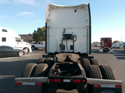 Peterbilt 579 tractor rear view showing fifth wheel and dual rear axles, white sleeper cab, chassis frame, and multiple tires in a dealership lot.
