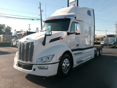 Peterbilt 579 highway tractor in white, front-left view, with aerodynamic sleeper cab and chrome grille.