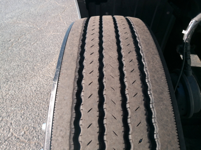 Peterbilt truck wheel/tire close-up showing tread pattern and wheel well in a sleeper tractor.