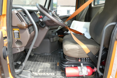 Volvo VNM42T truck cab interior showing steering wheel dashboard driver seat with seatbelt and floor mat.