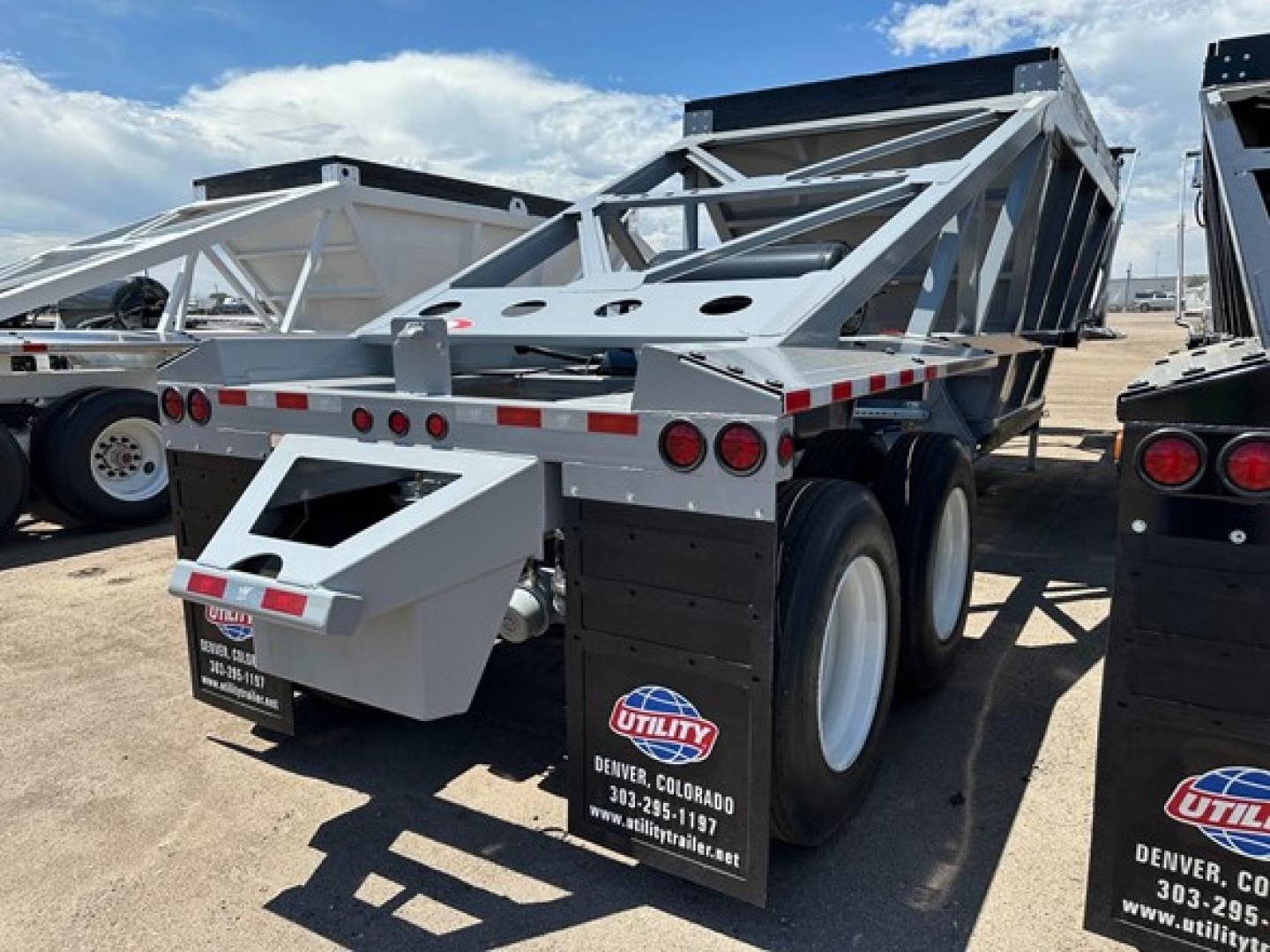 Trailer in-service bottom-dump trailer showing dual rear axles and utility brand mud flaps.