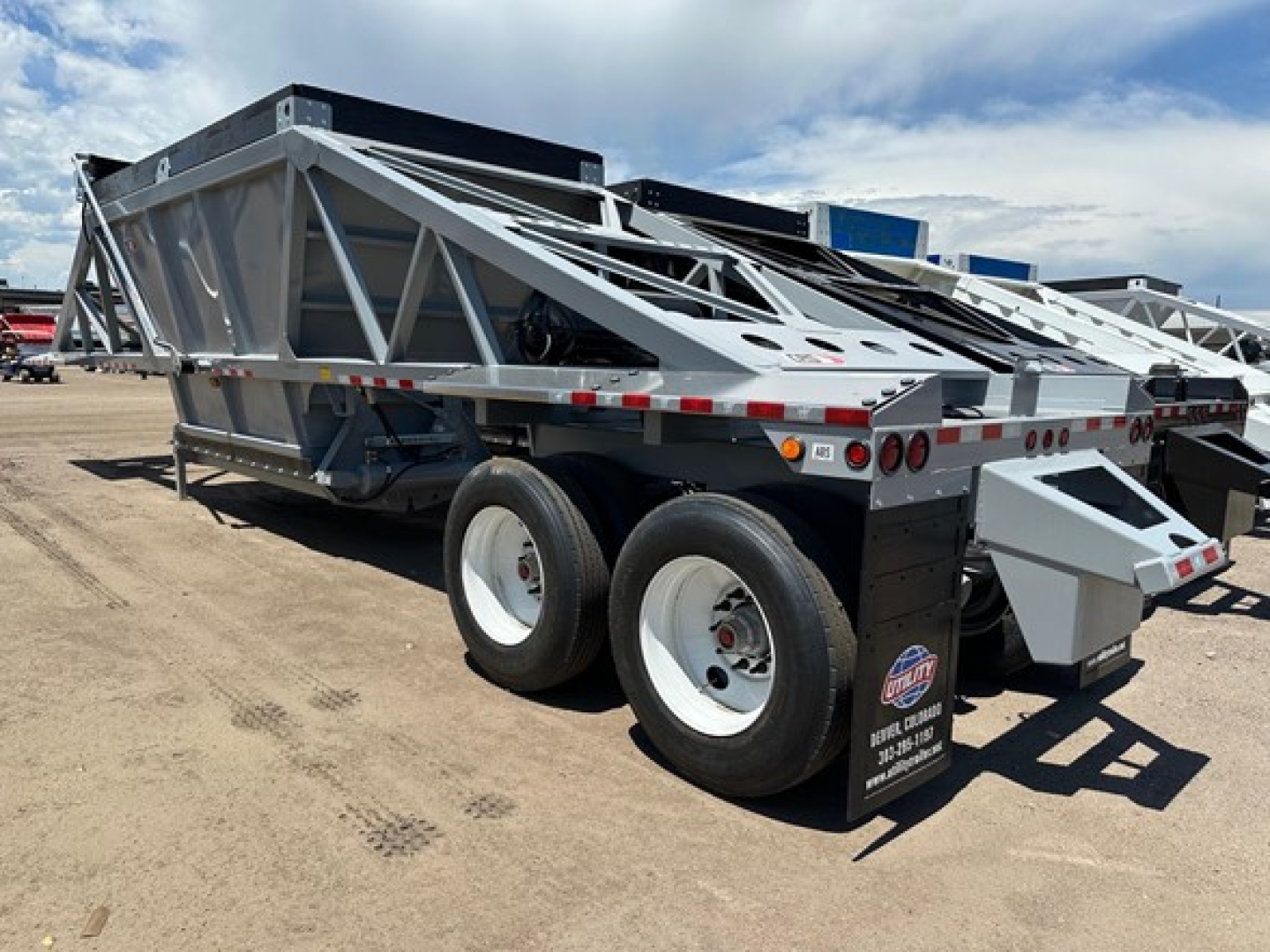 Bottom dump trailer showing dual axle with gray frame and rear discharge gate.
