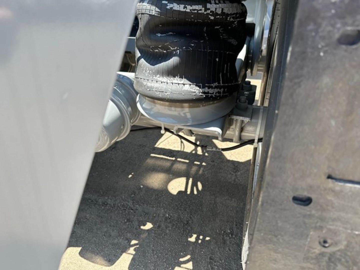 Bottom dump trailer wheel area with hydraulic or pneumatic suspension components and frame rails visible.