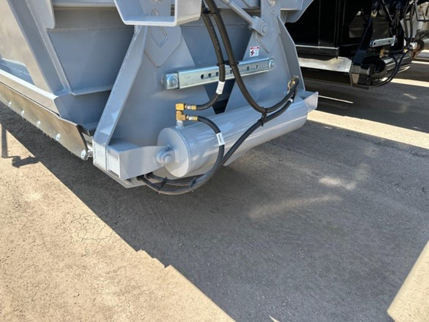 Low-angle view of a CPS light weight bottom dump trailer rear corner showing hydraulic actuator and wiring harness.