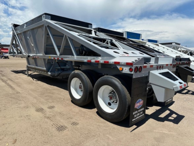 Bottom dump trailer with dual rear axles and silver frame, showing a triangular lattice structure and rear light cluster.