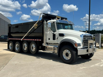 Dump truck 2027 Mack GR104F with white cab and black dump body, side view showing multiple rear axles and chrome grille.