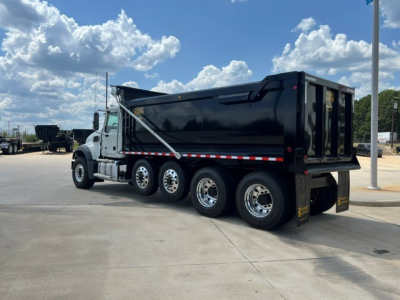 Dump truck side view showing Mack GR104F with black dump body and dual rear axles, chrome wheels, and silver cab accent. VIN sticker not visible.