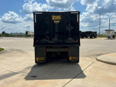 Rear view of a new 2027 Mack GR104F dump truck showing the black dump body, Mud flaps with Hilbilt Lufkin logos, and rear bumper with lights.