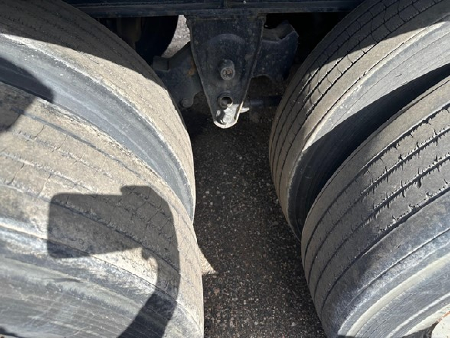 Trailer axle area showing dual rear tires and suspension mounting on a flatbed trailer.
