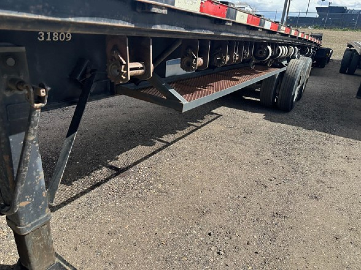 Trailer undercarriage showing steel flatbed with wooden deck and support steps in view.