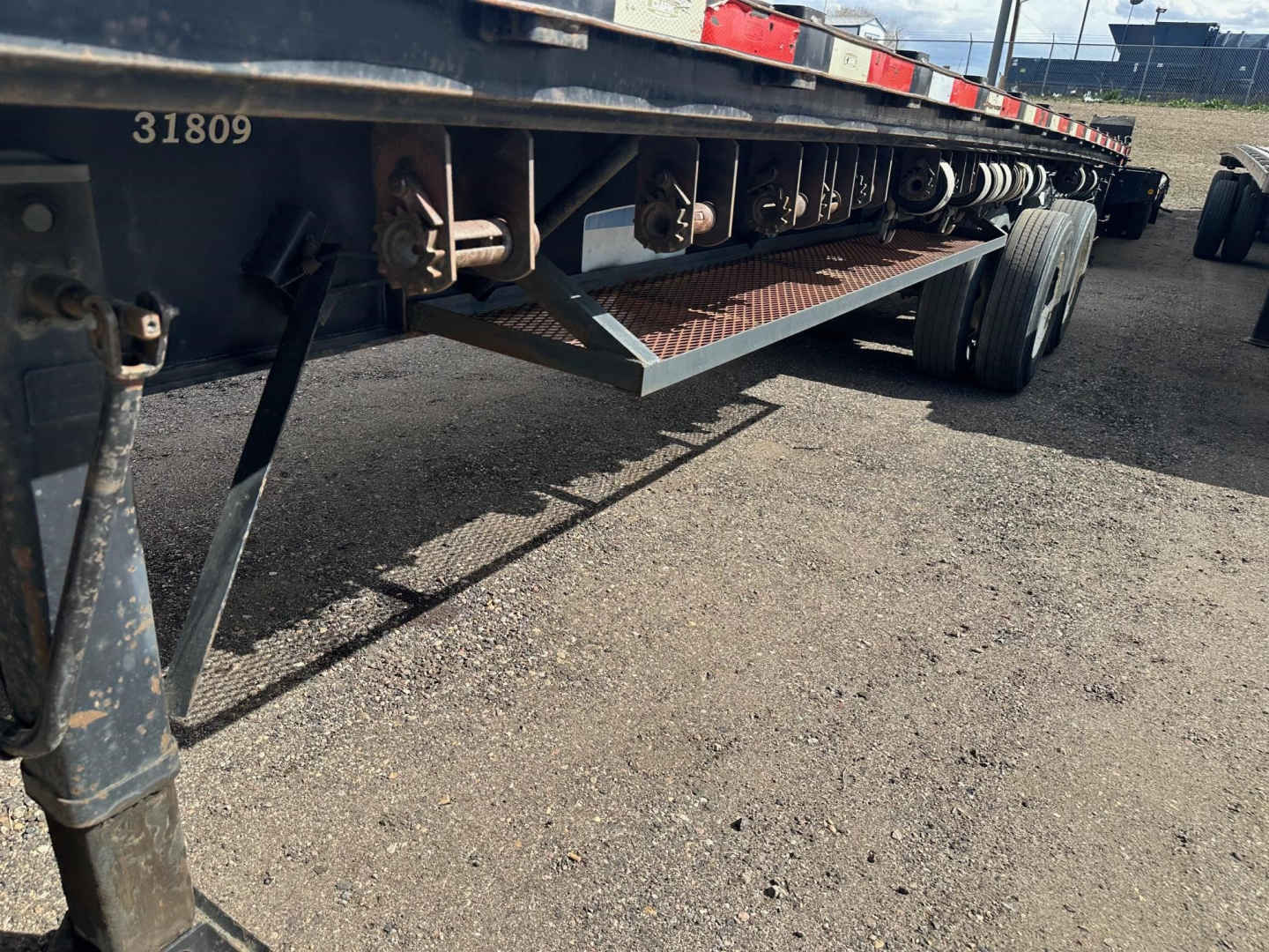 Trailer undercarriage showing structural beams and wheels; visible numbers '31809' on frame and a metal checker plate step.