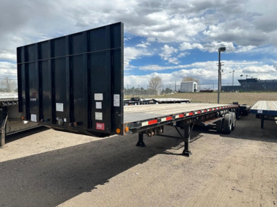 Flatbed trailer with wood deck kit and forklift support, 38 feet, steel construction, rear ramp/tilt gate, parked in lot.