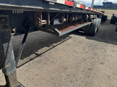 Trailer undercarriage showing steel flatbed with wooden deck and support steps in view.
