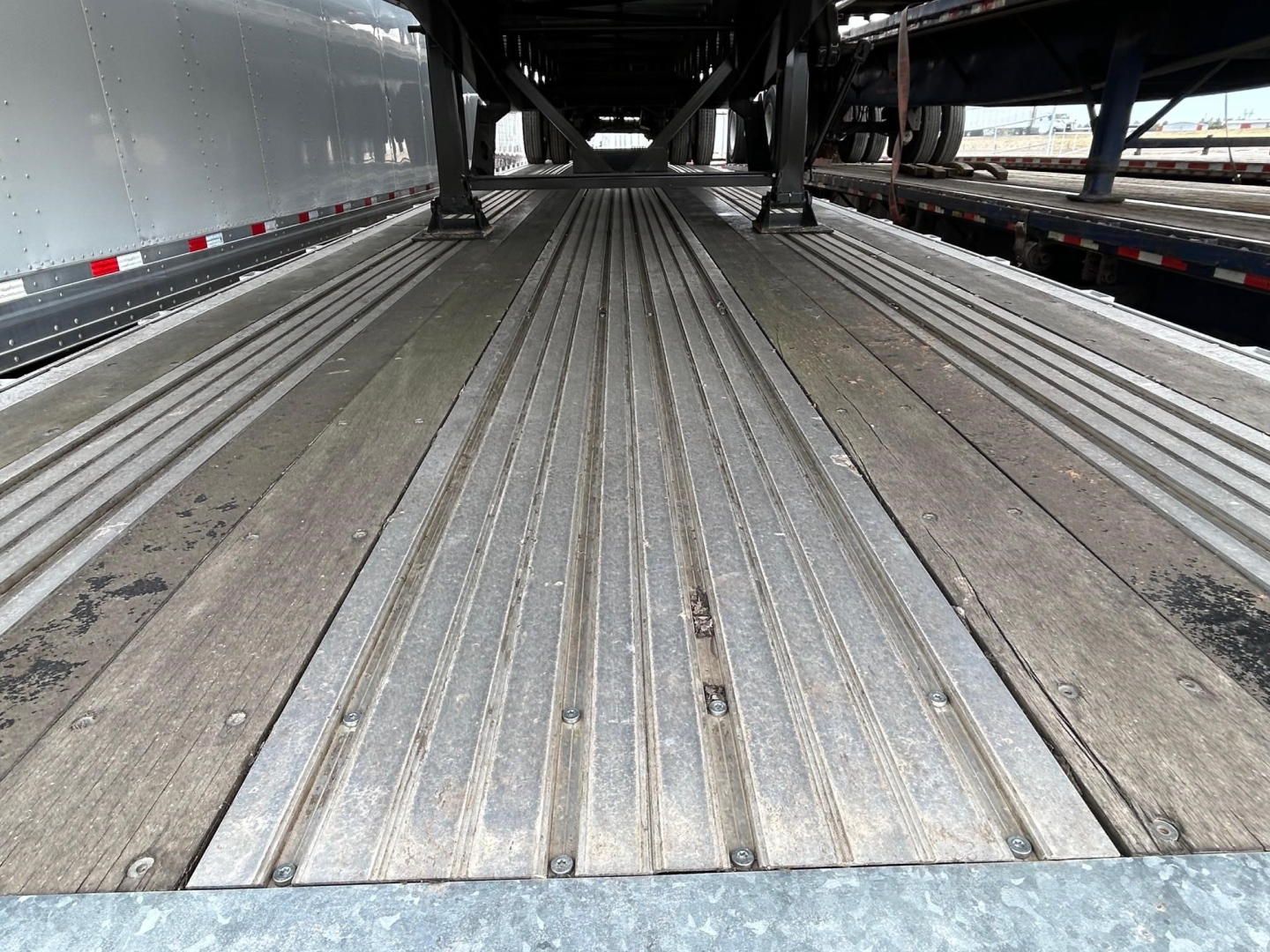 Trailer bed showing metal decking with multiple longitudinal power rails in a flatbed trailer interior.