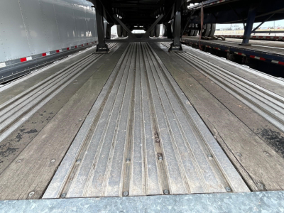 Trailer bed showing metal decking with multiple longitudinal power rails in a flatbed trailer interior.