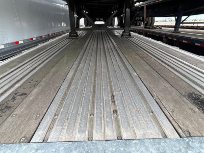 Trailer bed with corrugated aluminum planks and support beams, long flatbed trailer surface visible.