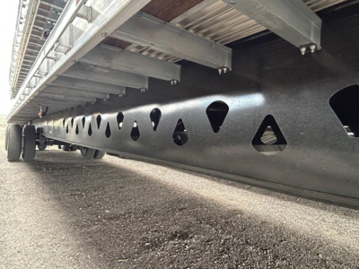 Manac Legend flatbed trailer underside showing welded steel frame with triangular cutouts and side rail supports.
