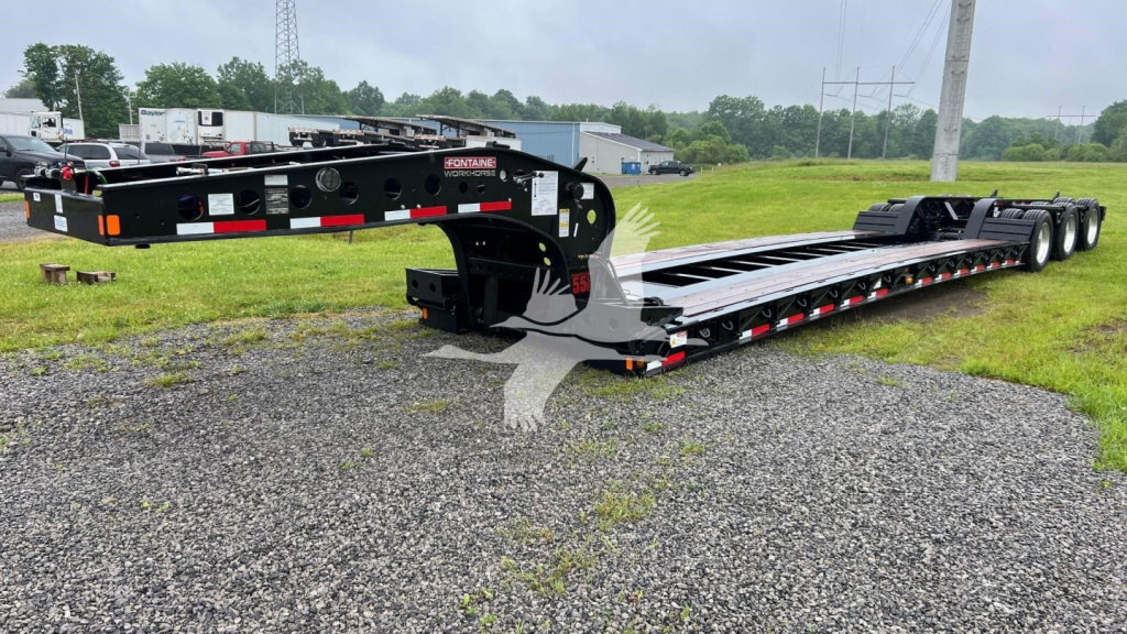 Fontaine lowboy trailer shown side view with black frame, long flatbed, triple-axle rear, and red/white reflective markings. Visible text includes 'FONTaine' on the side near the front, and additional stickers/labels unreadable at distance.
