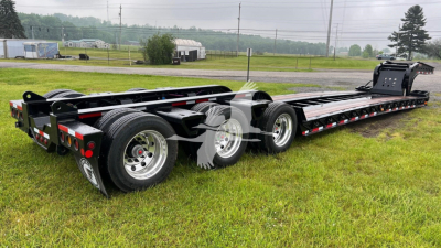 Fontaine 55 lowboy trailer in a grass lot, triple-axle with black frame and reflective red/white safety stripes; no visible branding text readable on the trailer.