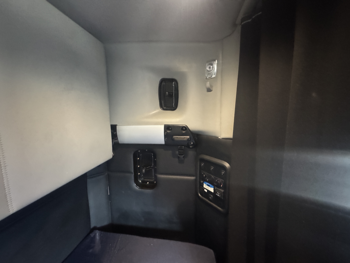 Kenworth T680 cab interior showing sleeper area and control panel with switches and storage compartments.