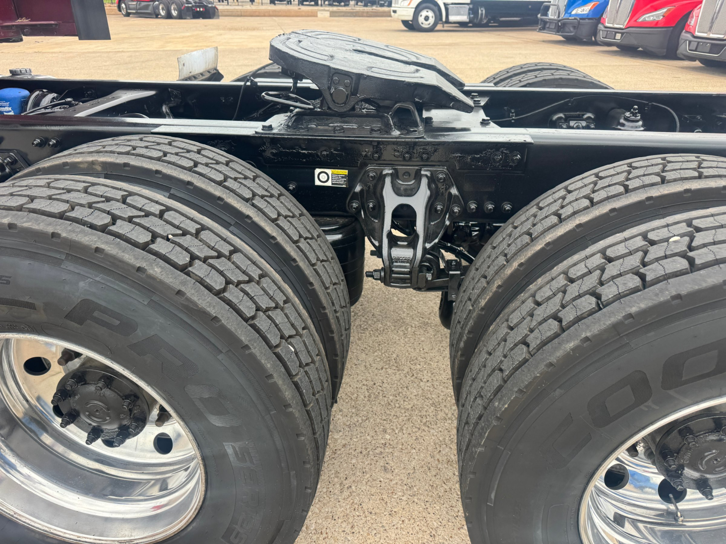 Kenworth T680 chassis with dual rear axles and tires; view of fifth wheel, frame, and suspension components under a sleeper cab.