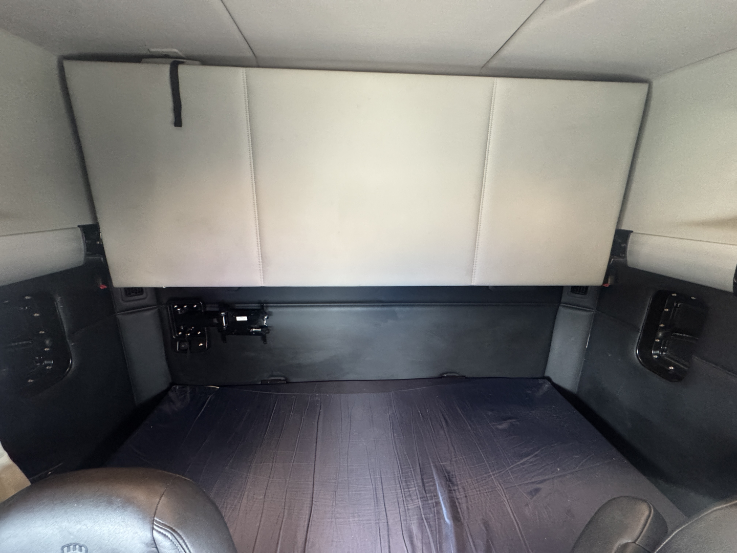 Interior cab view of a Kenworth T680 sleeper with a folded bunk area and dark storage compartments.