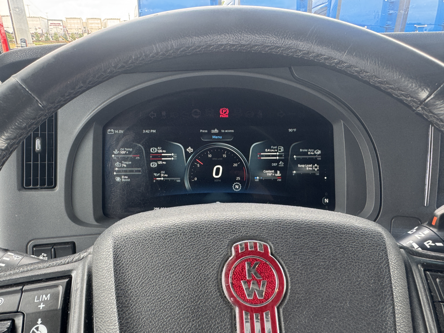 Kenworth T680 steering wheel with KW logo and digital instrument cluster displaying zero speed in 2023 model, dashboard controls visible.