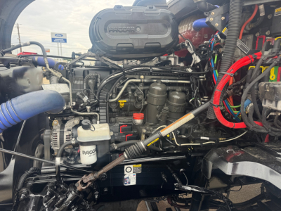 Kenworth T680 engine bay with Pacar radiator cover, hoses, wiring, and reservoirs visible.