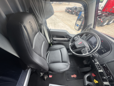 Kenworth T680 interior with driver's seat and steering wheel visible, dashboard controls and side window.
